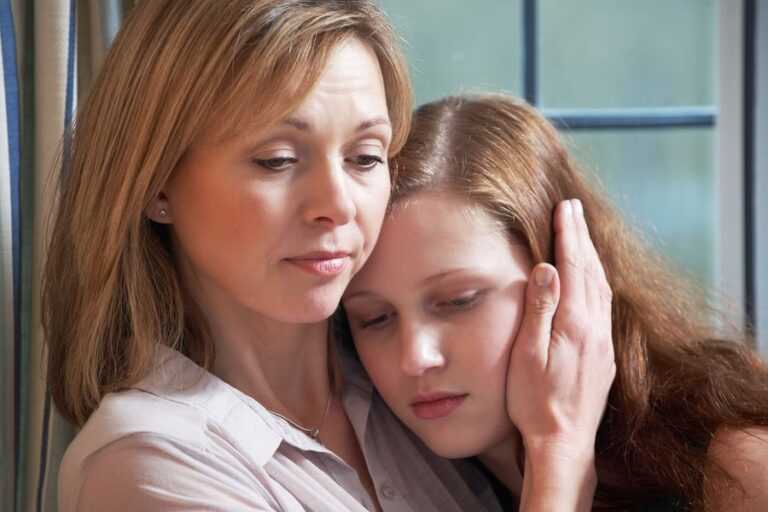 A concerned mother feeling guilt about a loved one's addiction embraces her teen daughter.