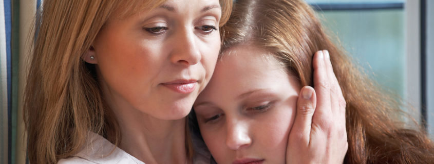 A concerned mother feeling guilt about a loved one's addiction embraces her teen daughter.