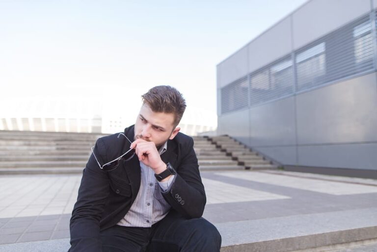 A business man sitting outside thinking about cocaine addiction signs.