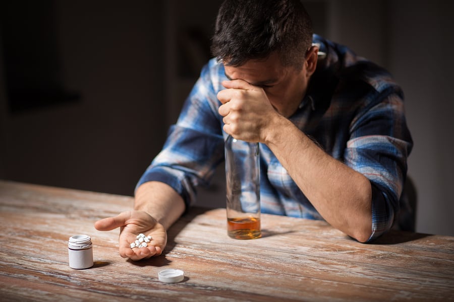 A man pouring a bottle of pain pills into his palm.