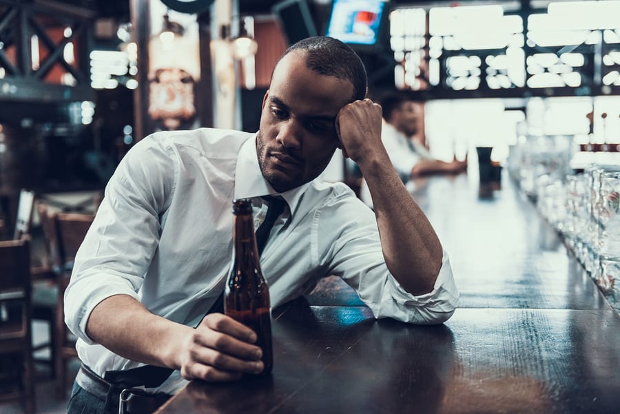A businessman sits at the bar with a beer in hand.