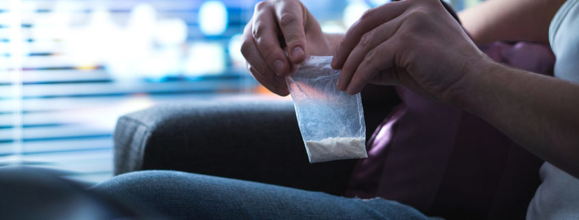 A drug addict closing a bag of meth.