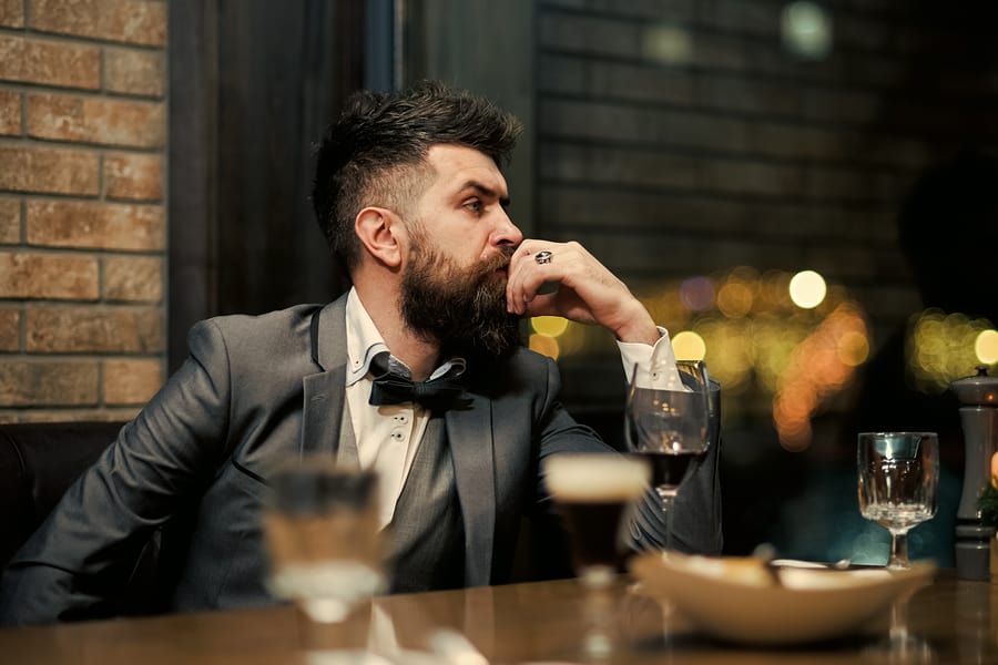 A businessman sitting at a bar consuming alcohol.