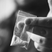 A hand holding out a bag of cocaine for depression.