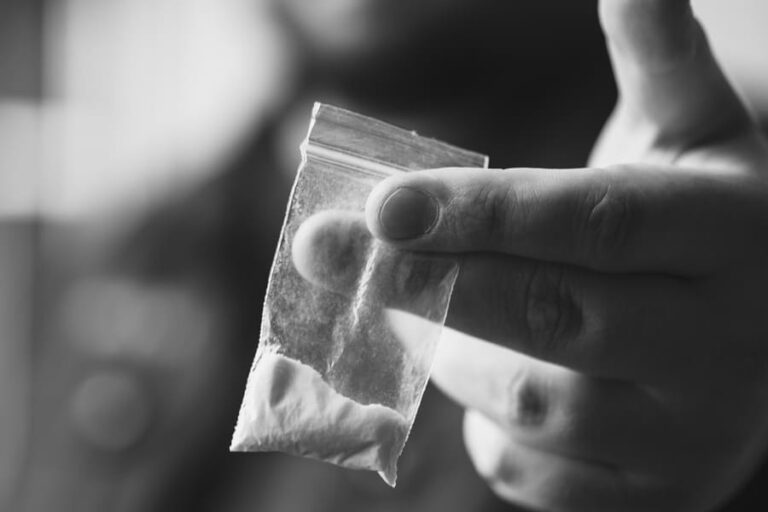 A hand holding out a bag of cocaine for depression.
