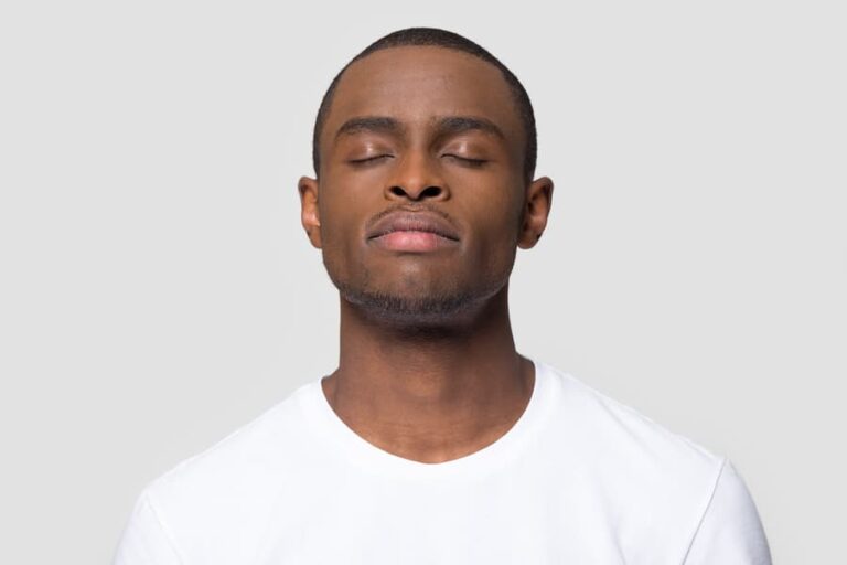 A man stands with his eyes closed and breathes deep