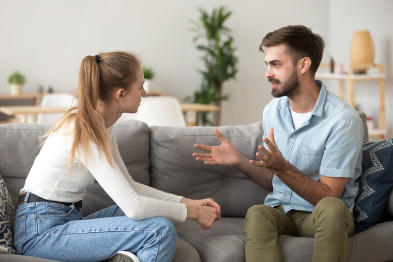 a couple sits on a couch and has a heated discussion