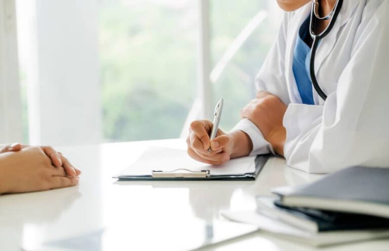 Amino Acid Benefits - A doctor sits at a table and writes on a piece of paper