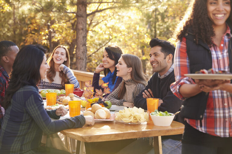 A group of friends sits together at a table outside and laughs