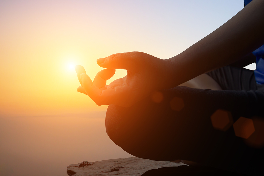 A woman practicing meditation in addiction recovery during sunset.