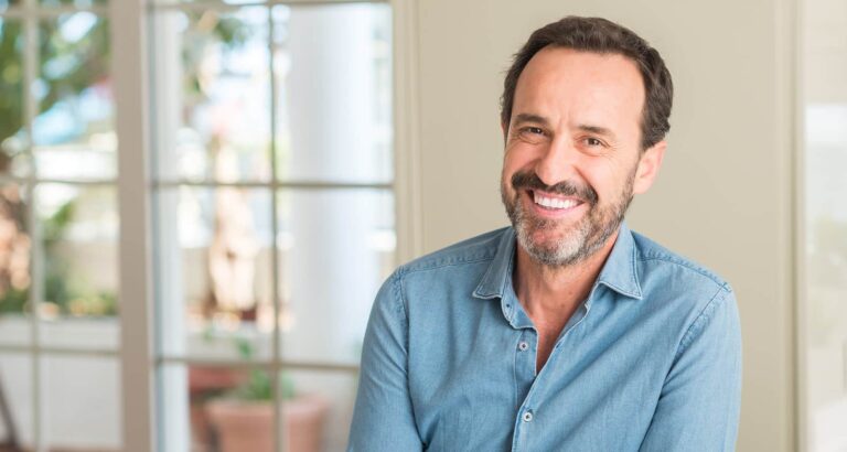 A man stands and smiles at the camera