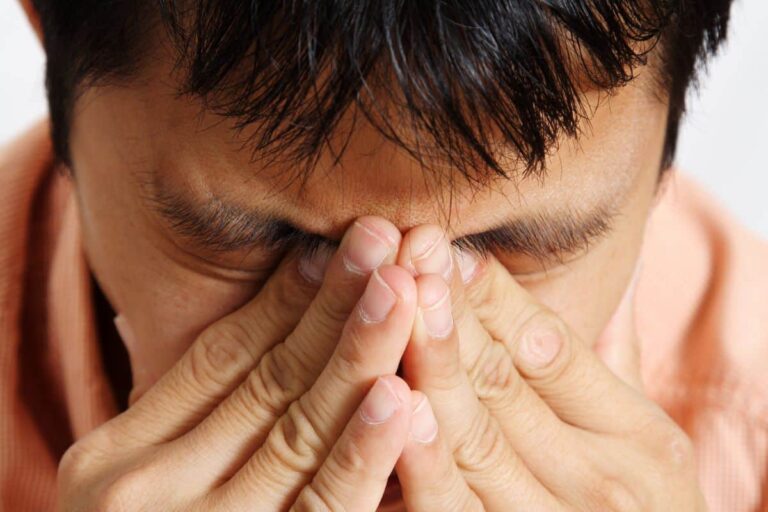 A stressed out man holds his hands to his face