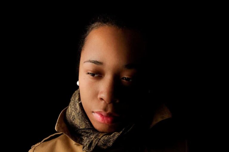 A woman looks into the distance with a sad expression