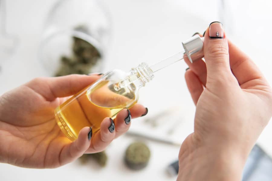 A woman’s hands holding CBD oil and considering CBD for pain management.