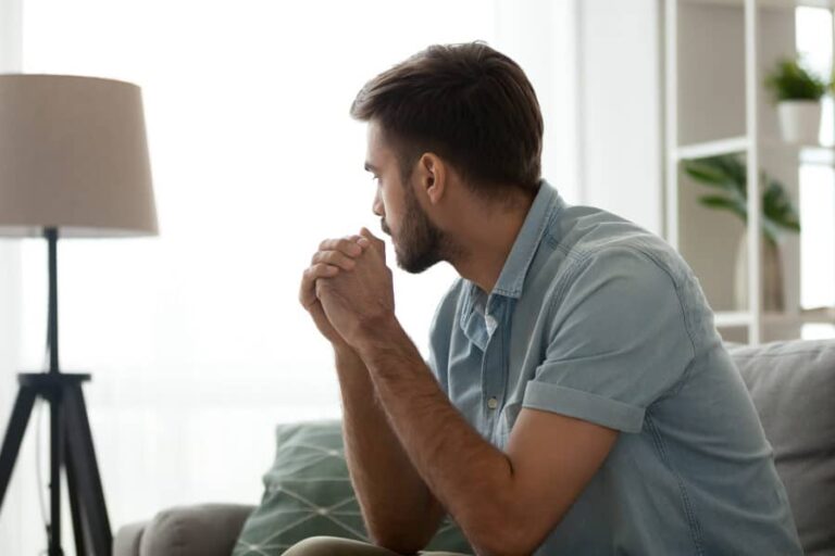 A man sits on the couch thinking about alcohol addiction in the LGBTQ community.