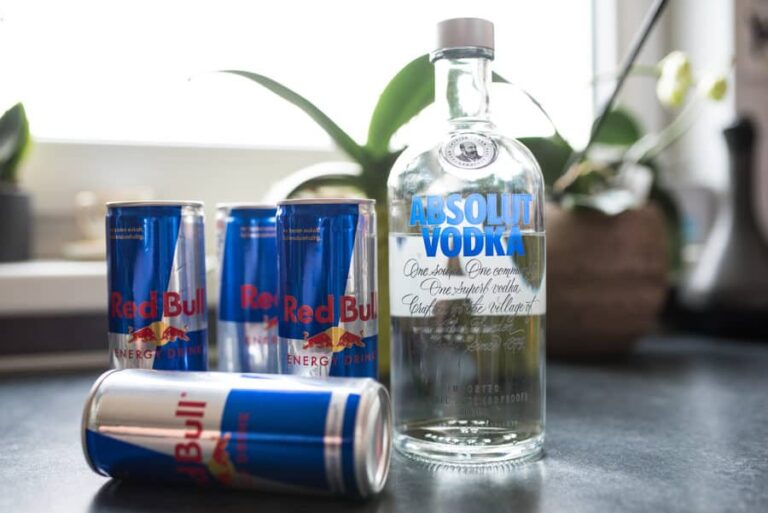 A photo of three Red Bull cans and one bottle of Vodka.