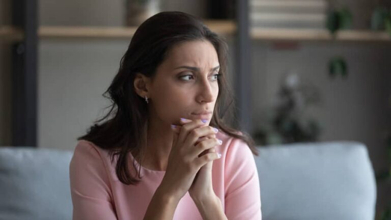 An anxious woman looks in the distance, thinking about the risks of leaving rehab early.