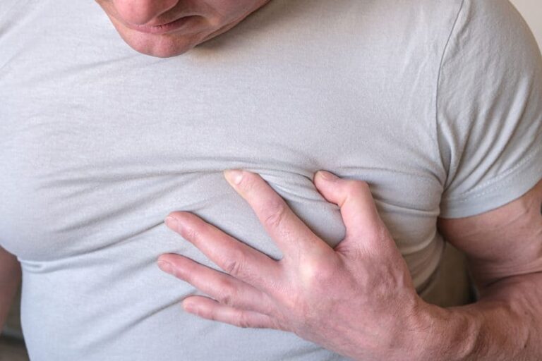 A man grabs his hands and places them on his heart in pain.