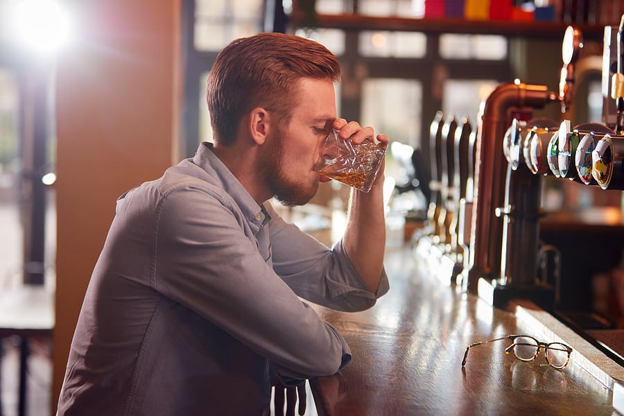 A man sits at a bar and drinks alone