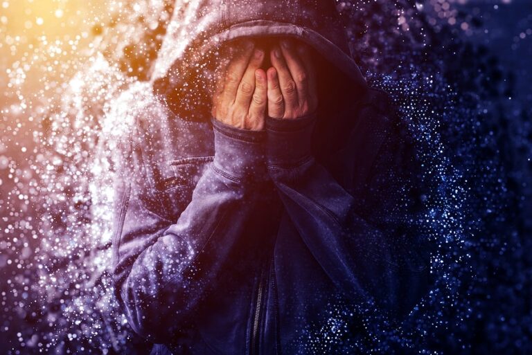 A person buries their face in their hands while crying