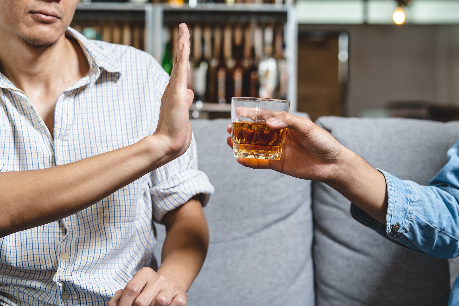 Man refuses alcoholic beverage being offered to him by friend.