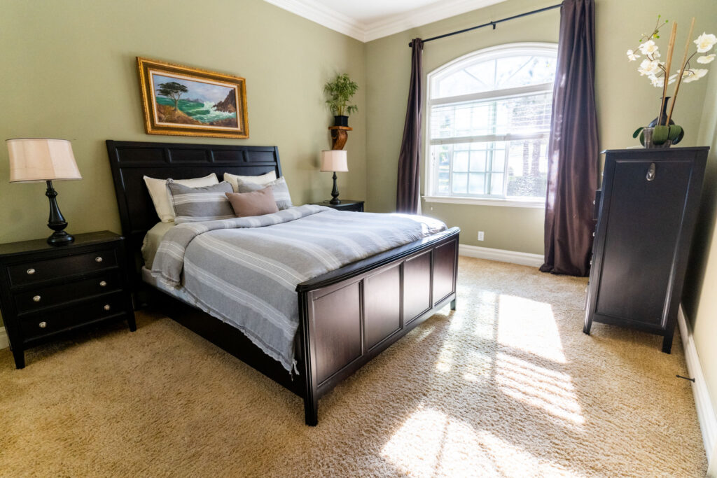 A king bedroom with a large window, side table and dresser