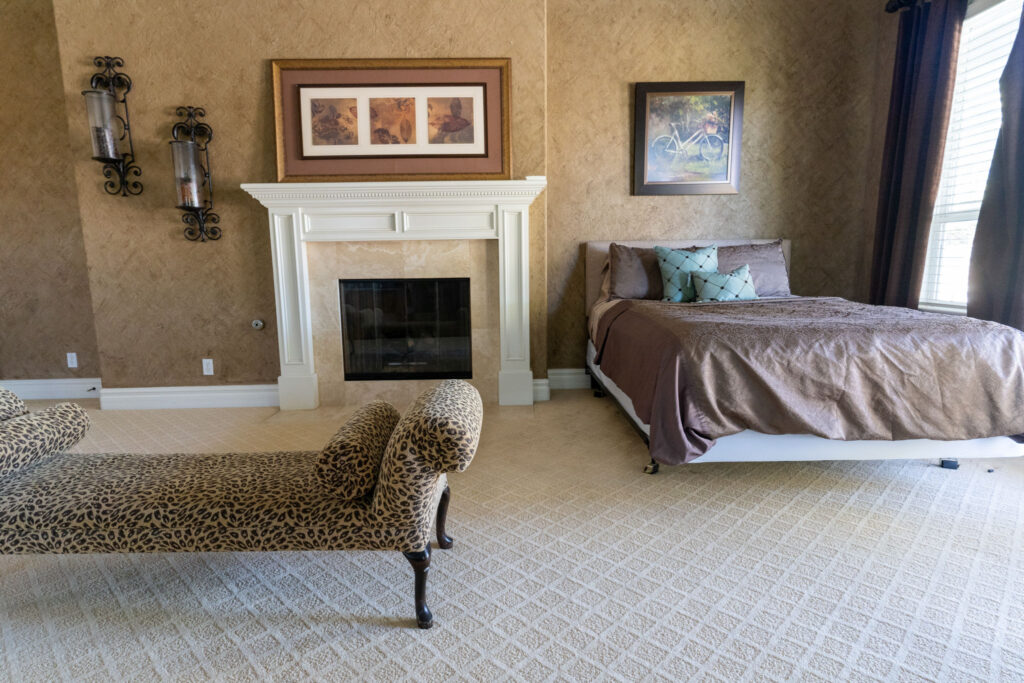 A queen bed next to a fireplace and a resting chaise