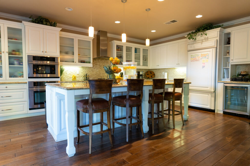 A kitchen with a large marble top island and high top seating