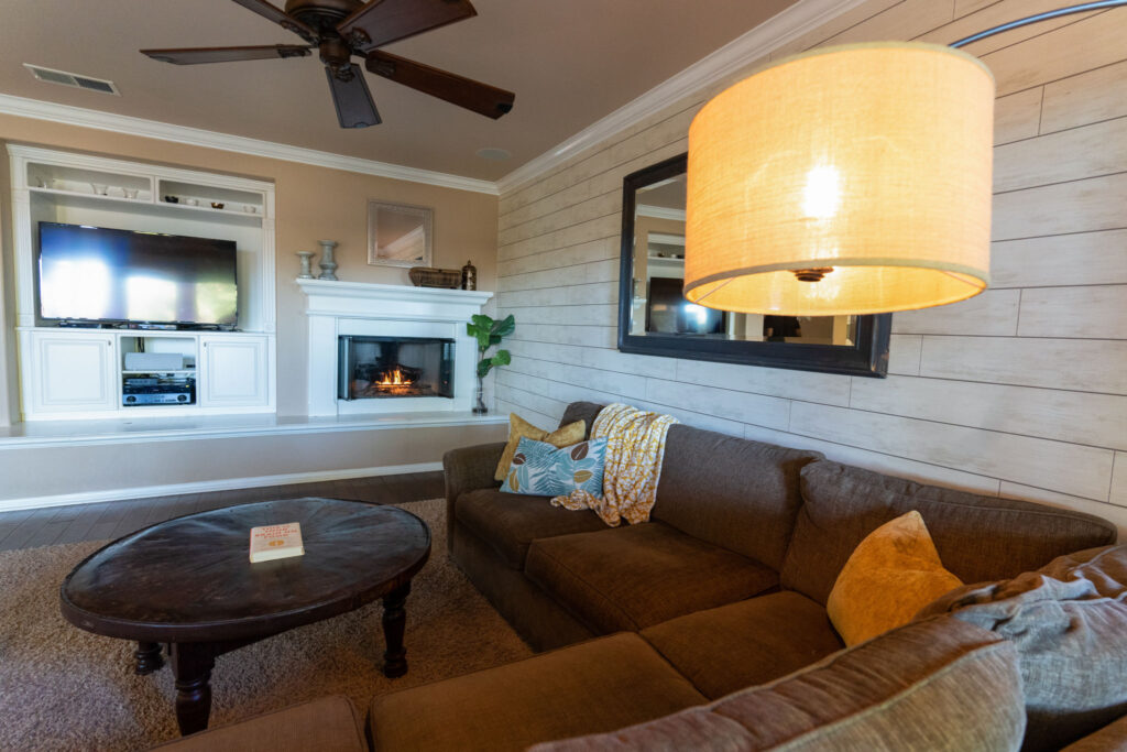A living room with an L shaped sectional couch, TV and fireplace